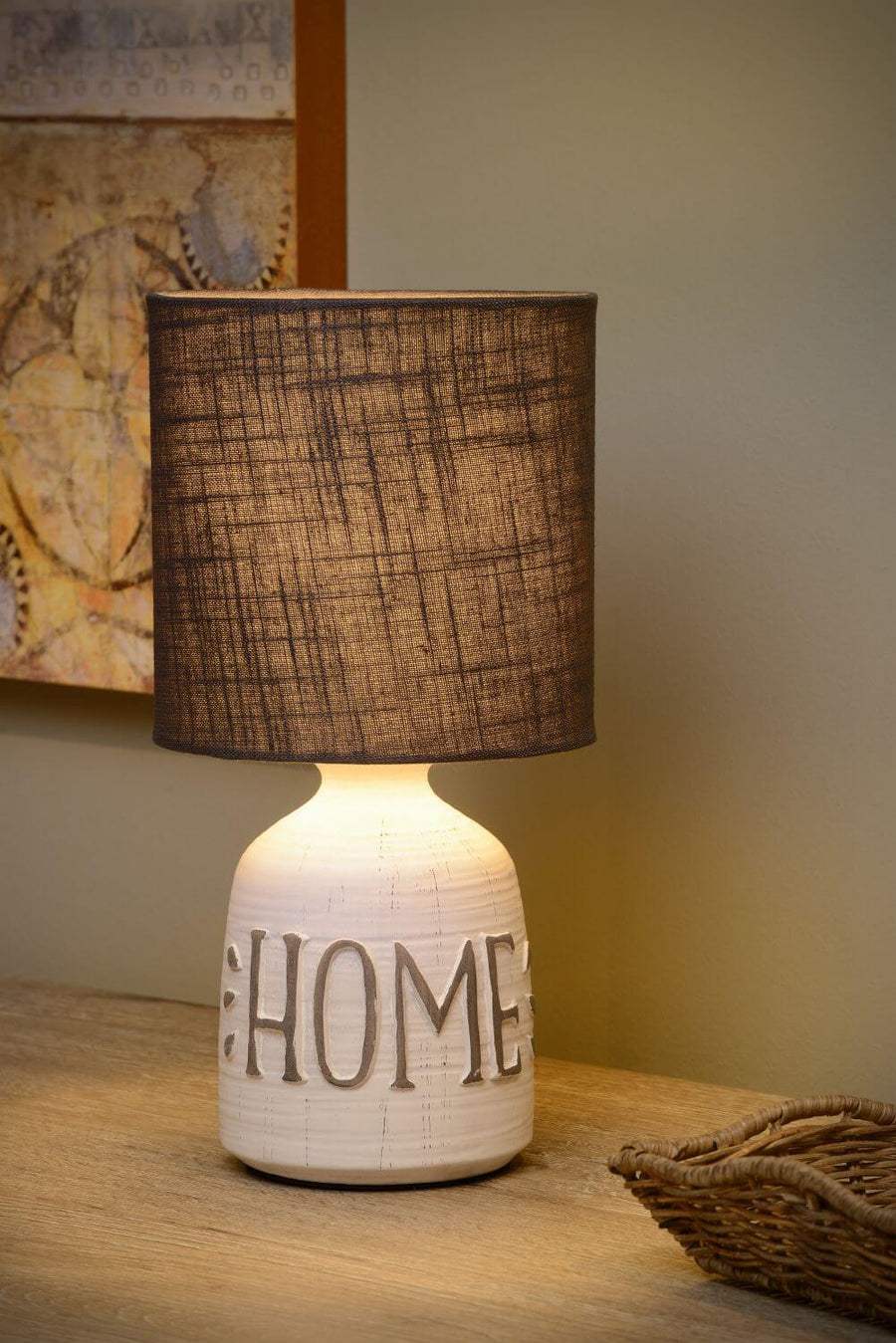 Gros plan de la lampe allumée, abat-jour en coton et lettrage HOME.
