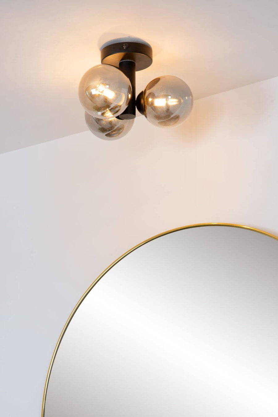 Détail de la fixation au plafond et des trois globes allumés près du miroir.