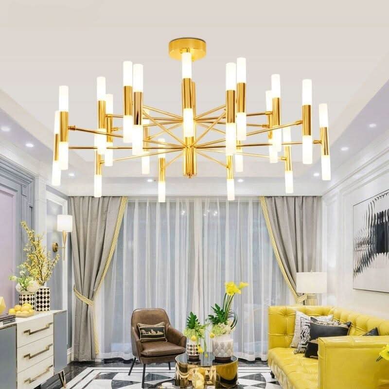 Grand lustre doré éclairant un salon lumineux avec canapé jaune et rideaux.