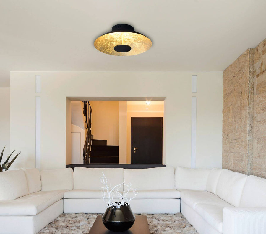 Plafonnier allumé au plafond d'un salon blanc avec canapé d'angle
