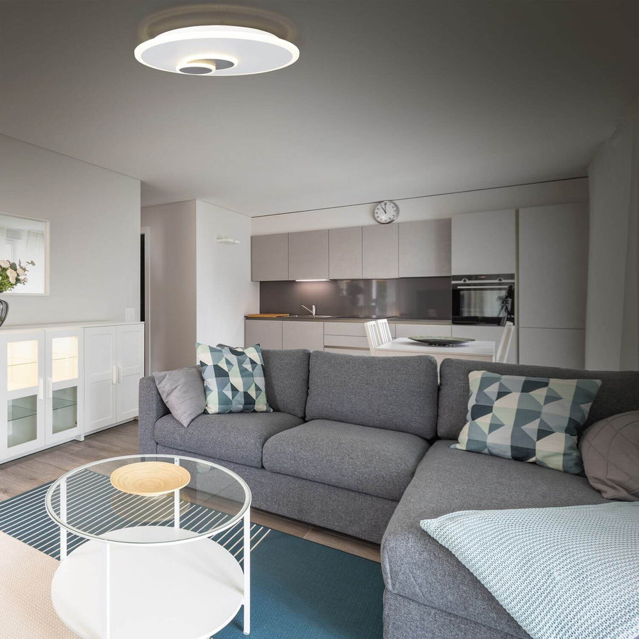 Luminaire éclairé au-dessus d'un canapé gris dans un séjour avec cuisine