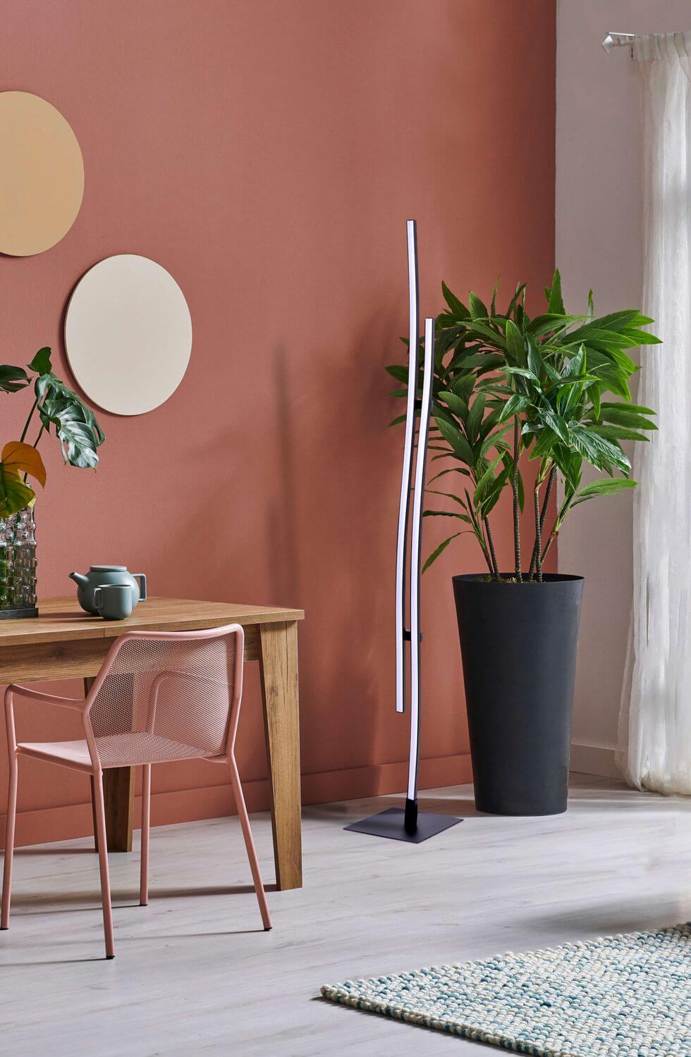 Lampadaire noir dans une salle à manger au mur terracotta et grande plante