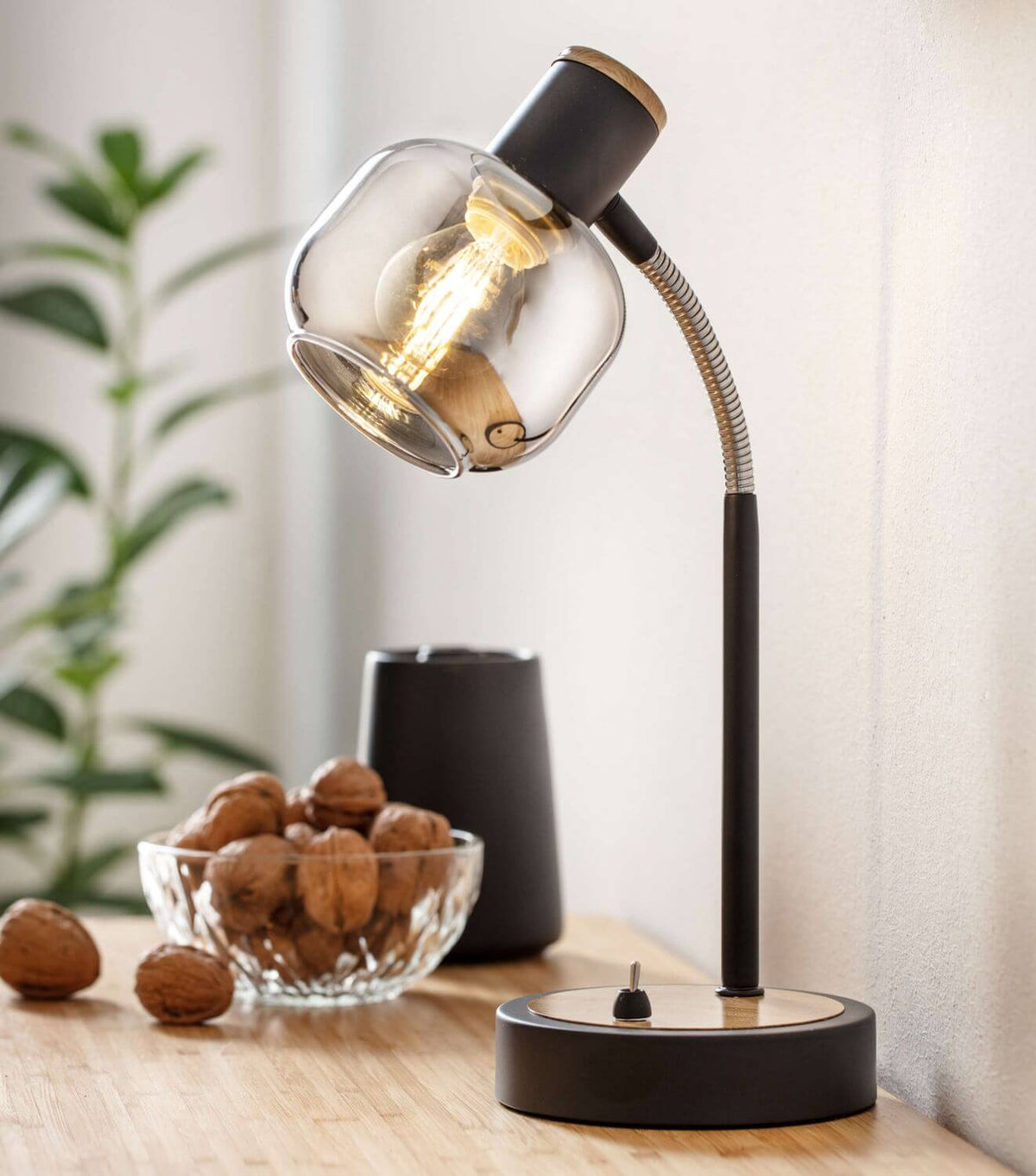 Lampe allumée près d'un bol de noix et d'un vase noir