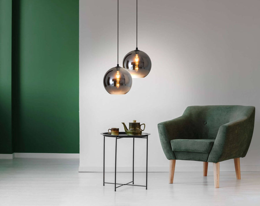 Deux suspensions en verre fumé suspendues devant un fauteuil vert dans un intérieur