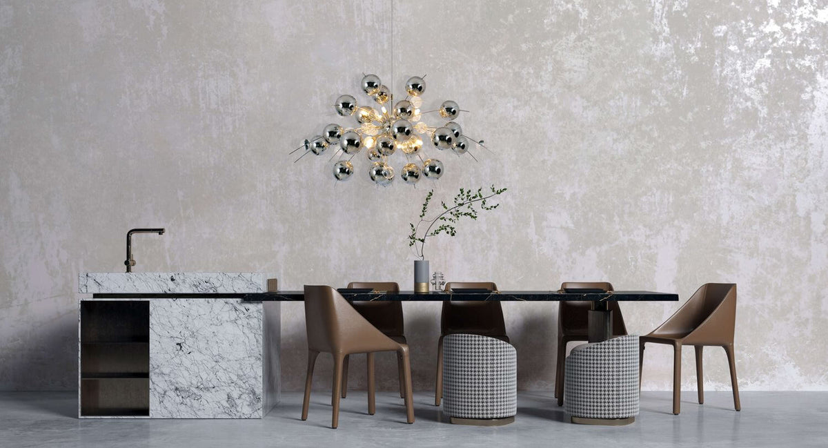 Suspension chromée au-dessus d'une table de salle à manger, mur texturé et cuisine marbre.