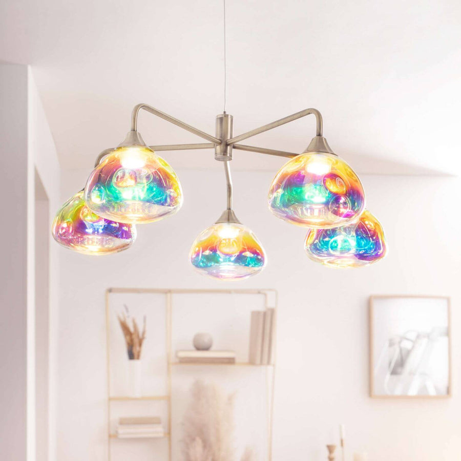 Luminaire suspendu allumé, verre irisé multicolore dans un intérieur blanc lumineux.