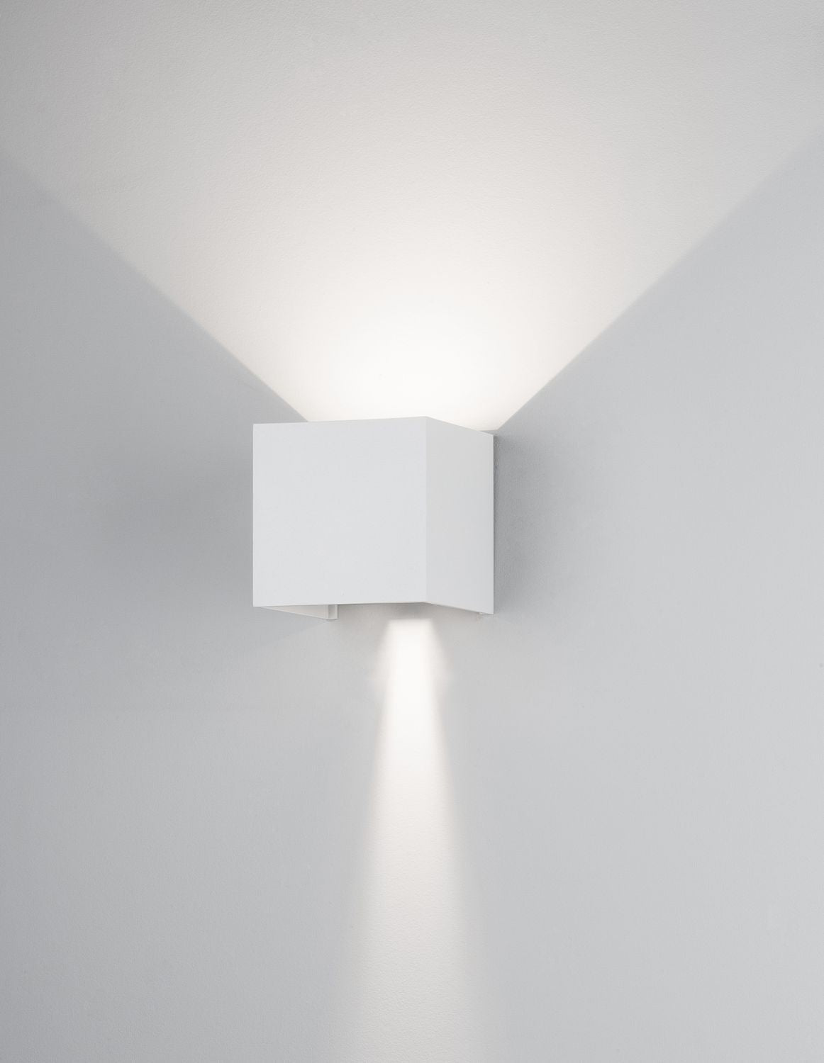 Applique carrée blanche allumée sur mur gris, halo haut et bas