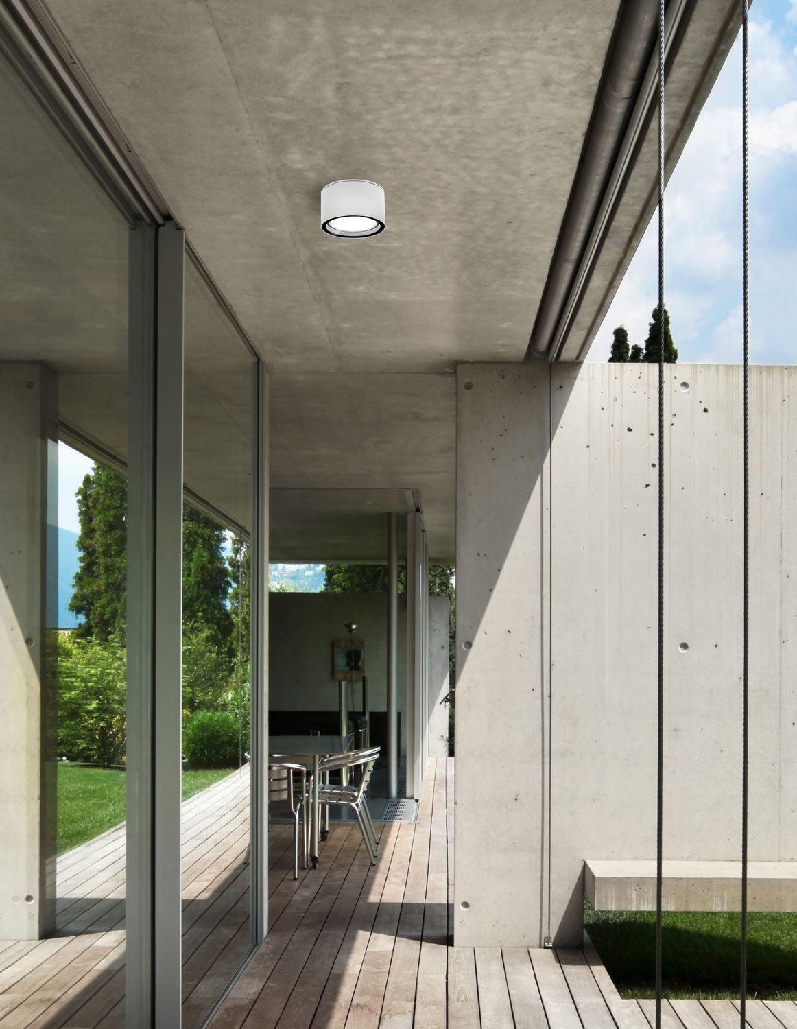 Plafonnier blanc fixé sous une terrasse en béton, mise en ambiance extérieure