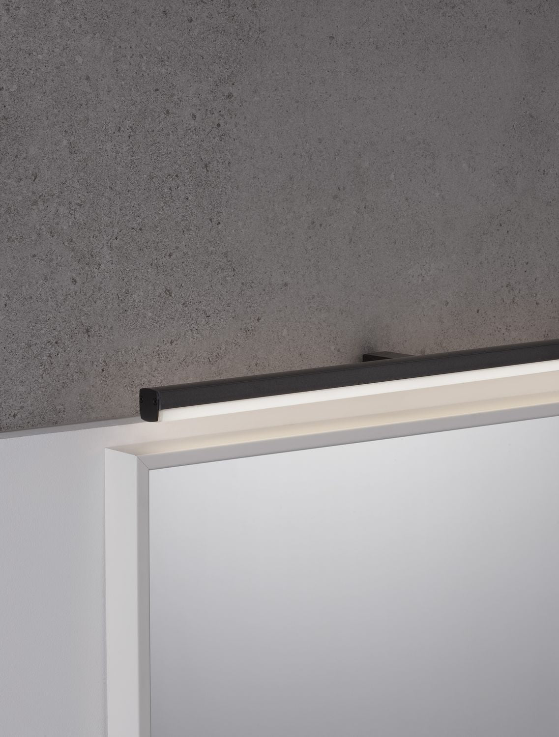 Applique murale noire allumée au-dessus d'une tête de lit blanche, ambiance chambre
