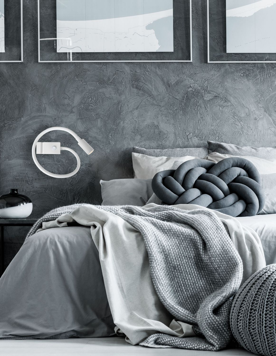 Applique murale blanche allumée au-dessus d'un lit dans une chambre grise