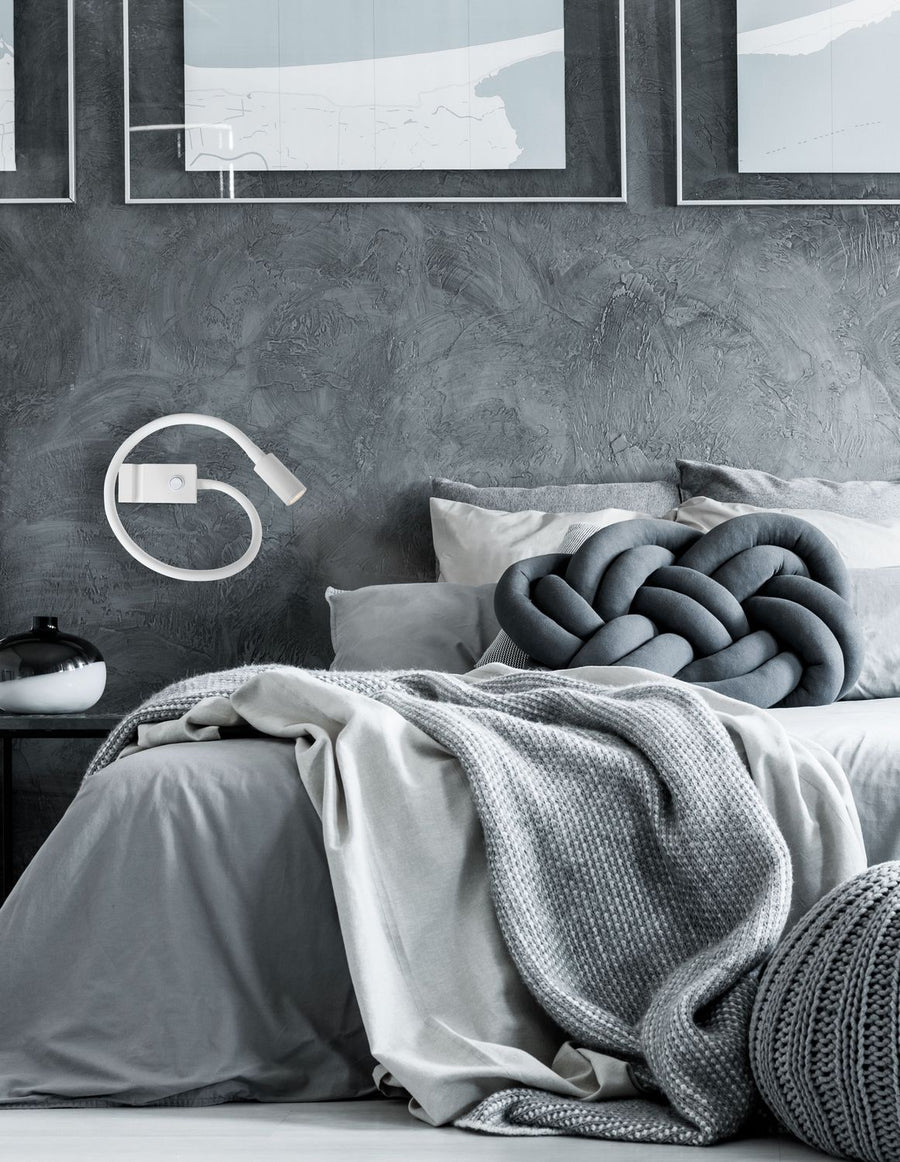 Applique murale blanche allumée au-dessus d'un lit dans une chambre grise