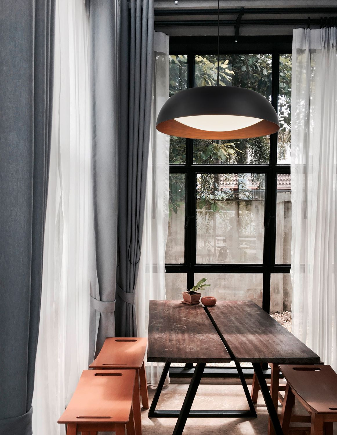 Suspension noire allumée au-dessus d'une table en bois, mise en ambiance intérieure