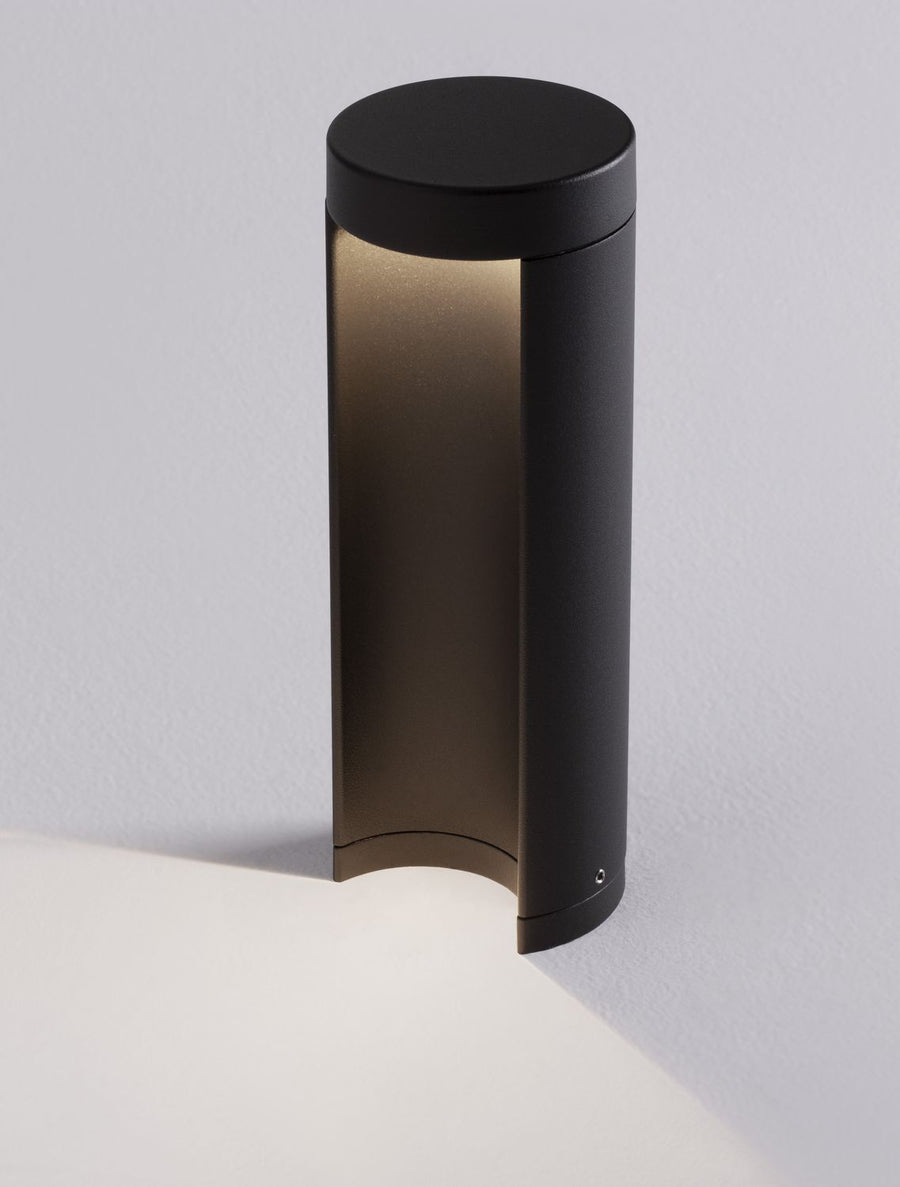 Détail rapproché du cylindre noir et du verre éclairé contre un mur gris