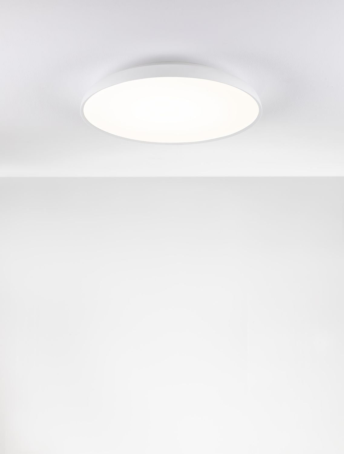 Plafonnier rond blanc allumé, fixé au plafond, lumière diffuse uniforme