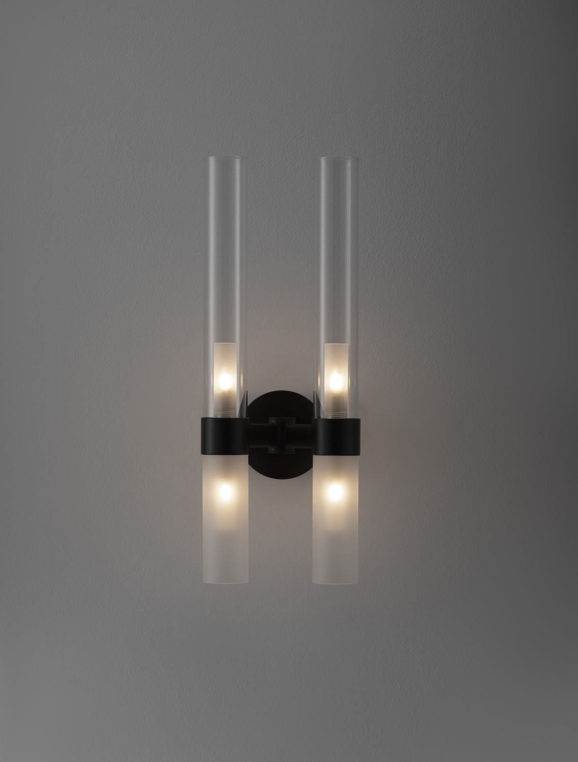 Applique allumée sur mur gris, halos lumineux diffusés vers le haut et le bas