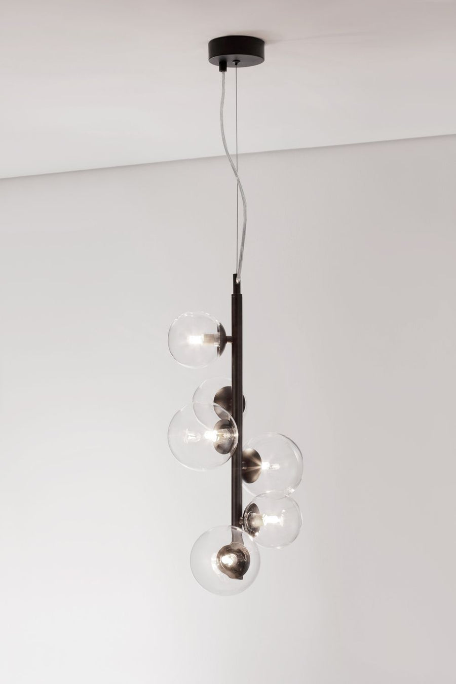 Luminaire allumé sur fond clair, ampoules visibles à l'intérieur des globes transparents