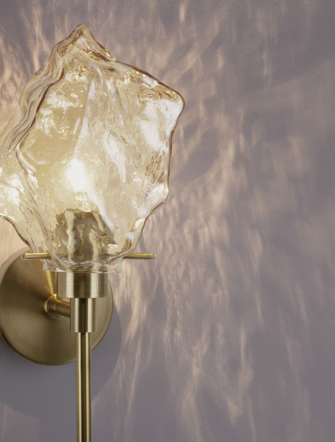 Détail du verre froissé diffusant une lumière chaude et ses reflets muraux