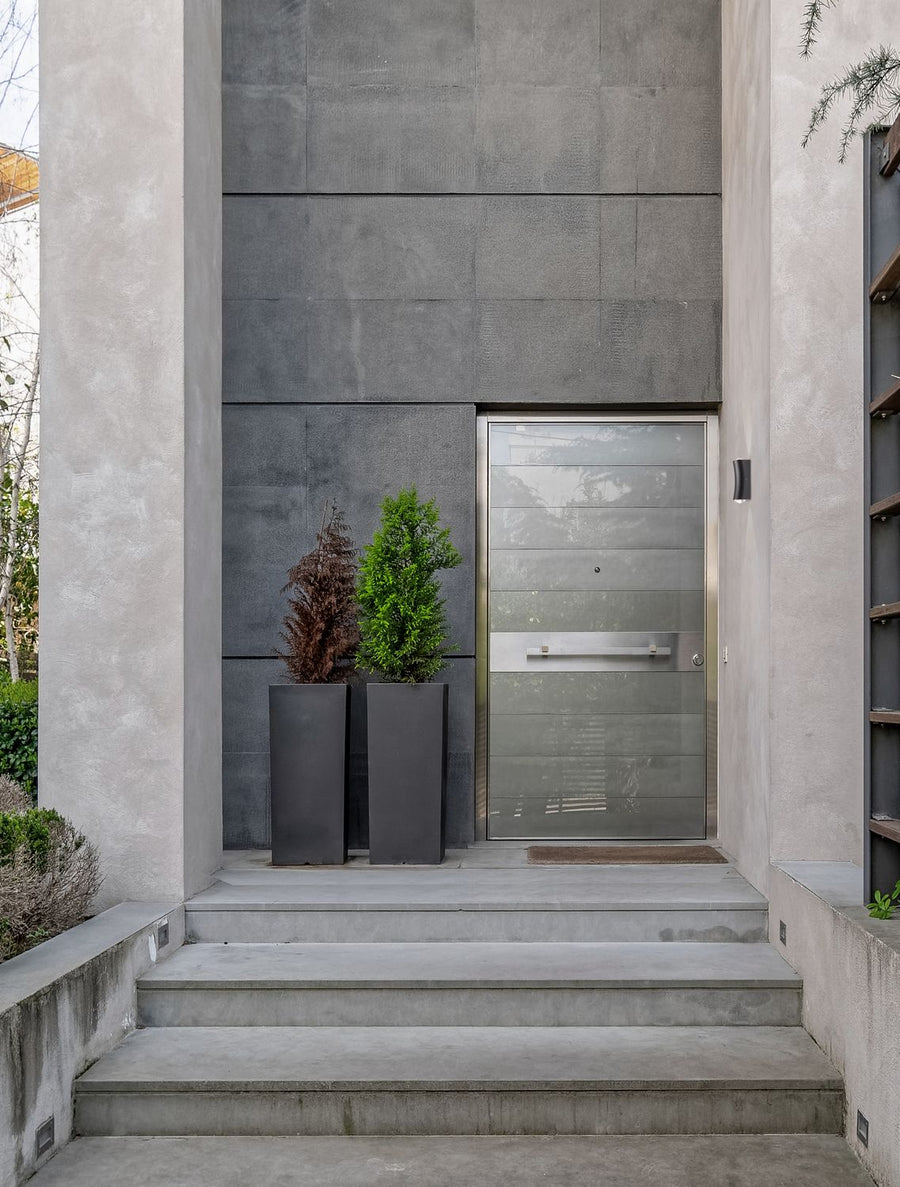 Entrée moderne en béton gris avec applique murale noire près de la porte