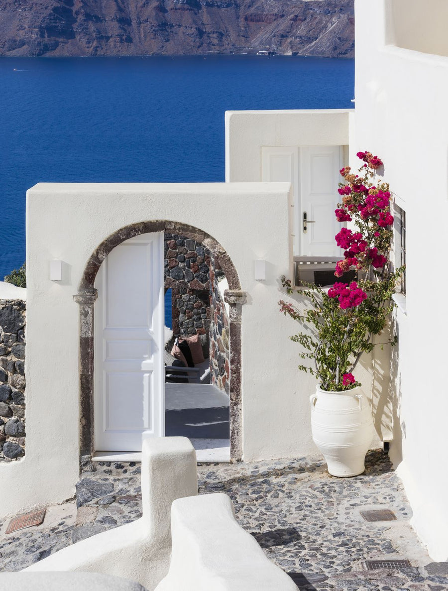 Deux appliques blanches fixées sur une façade blanche près d'une porte cintrée, vue de Santorin