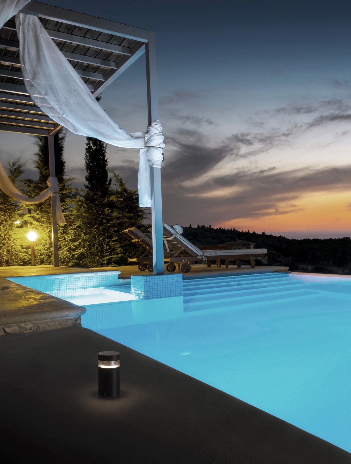 Borne noire allumée au bord d'une piscine au crépuscule