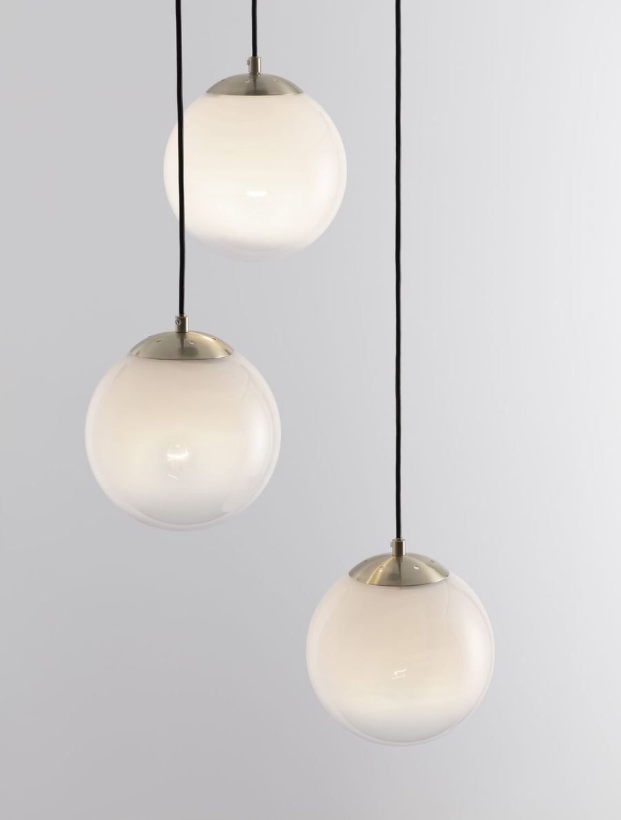 Détail rapproché des calottes dorées et des globes allumés en verre opalin