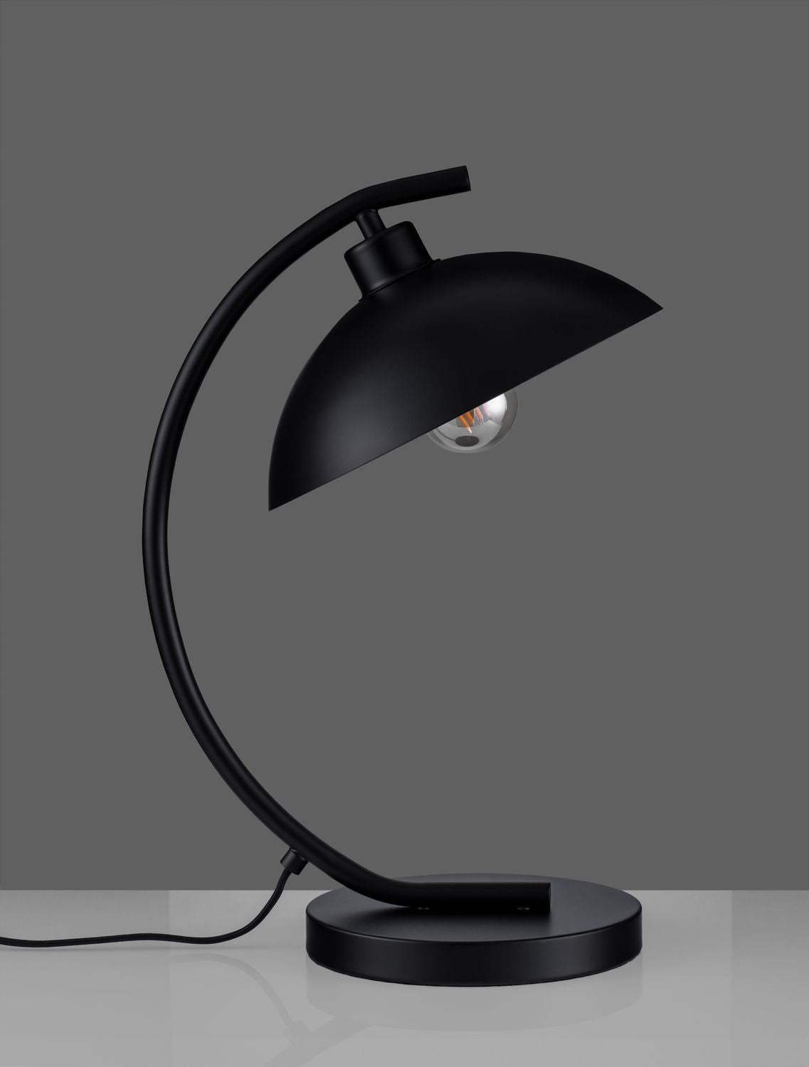 Vue de profil sur fond gris, lampe noire avec bras recourbé et câble apparent.