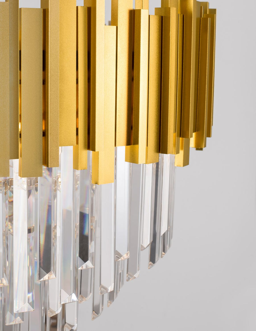 Gros plan sur les lamelles dorées et les prismes de cristal du luminaire.