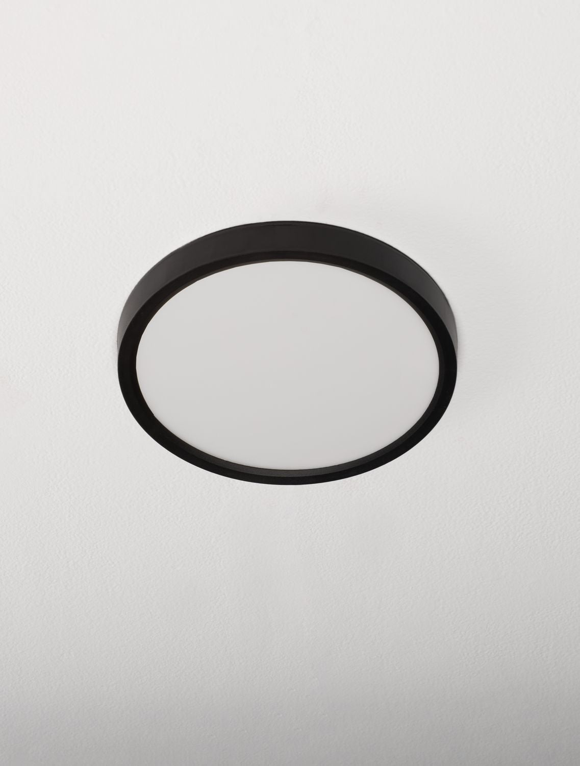 Plafonnier rond fixé au plafond blanc, vue légèrement en contre-plongée
