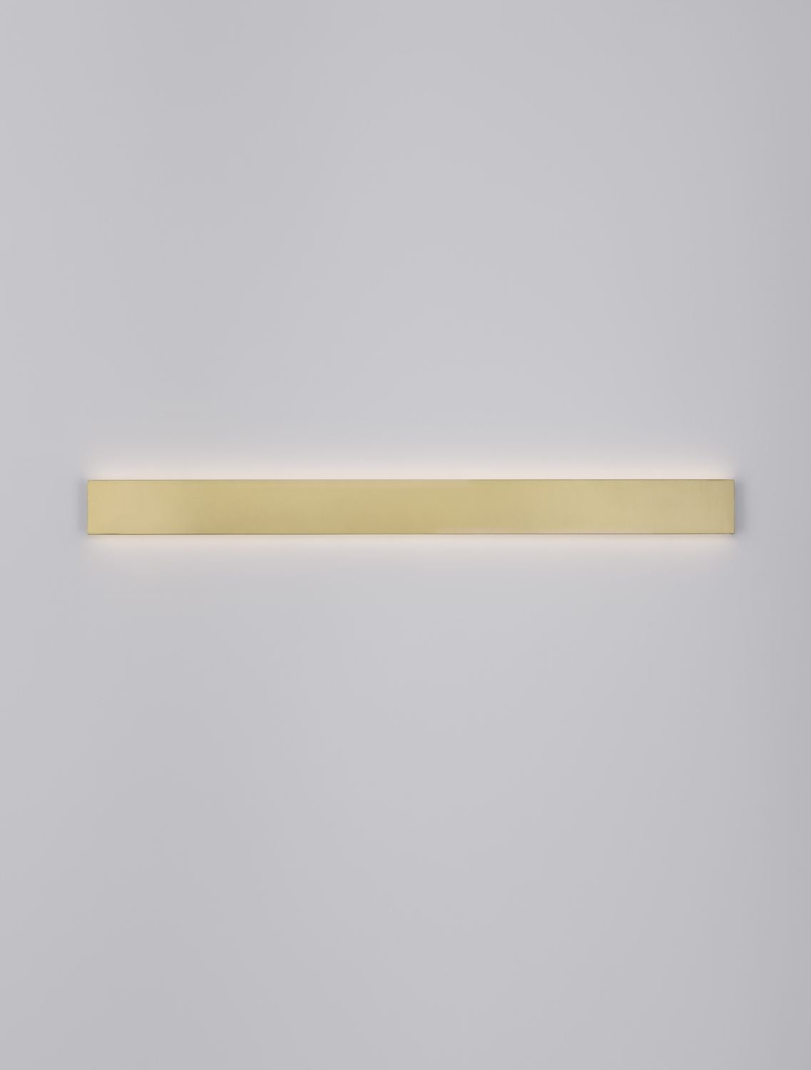 Bandeau doré allumé projetant une lumière rasante sur le mur blanc