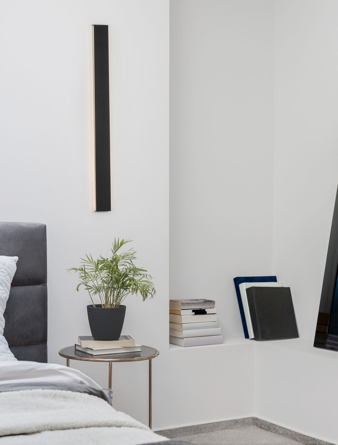 Applique murale noire allumée au-dessus d'une table de chevet dans une chambre