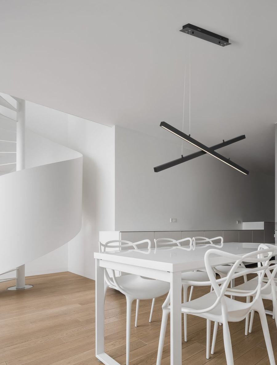 Suspension noire en croix installée au-dessus d'une table blanche dans une salle à manger