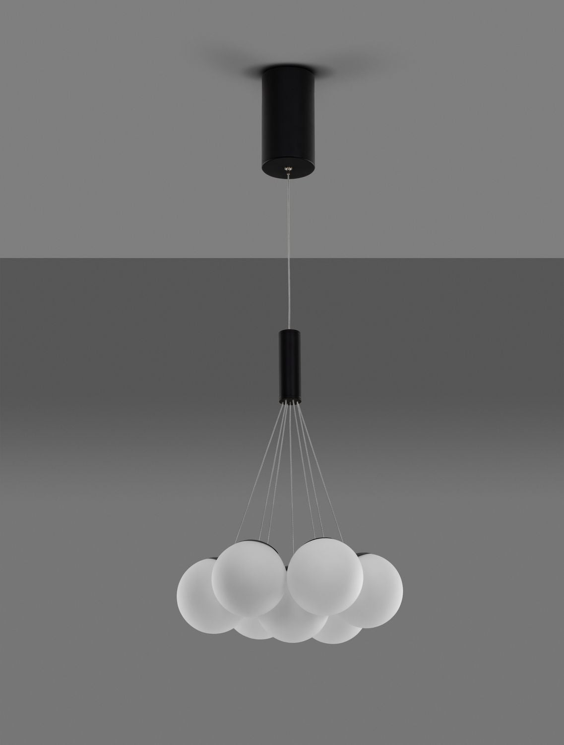 Suspension éclairée sur fond gris, lumière douce diffusée par les boules de verre
