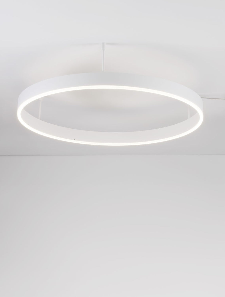 Vue en contre-plongée du luminaire allumé, montrant l'anneau blanc et la lumière diffuse vers le bas.