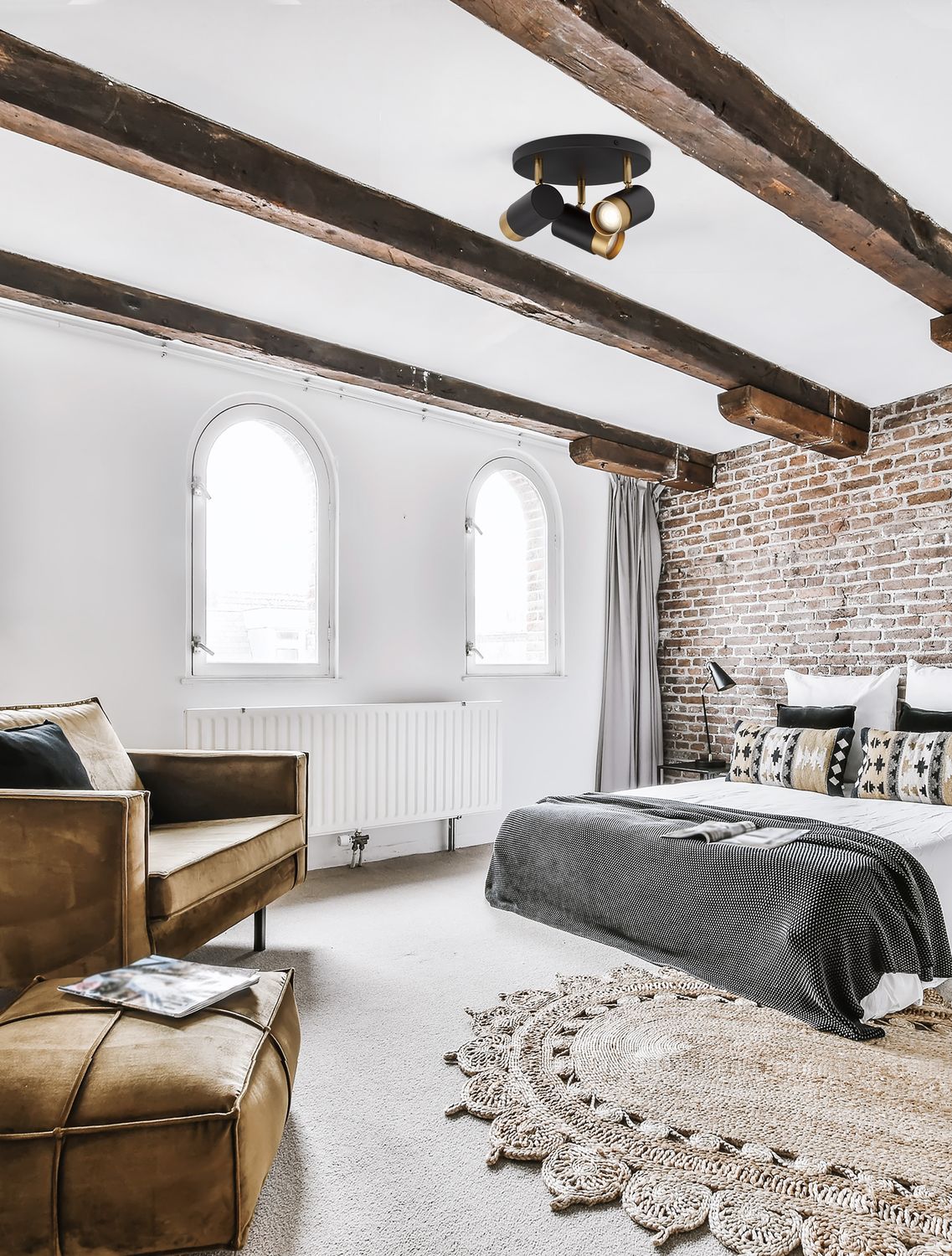 Plafonnier noir et laiton fixé au plafond à poutres d'une chambre style industriel