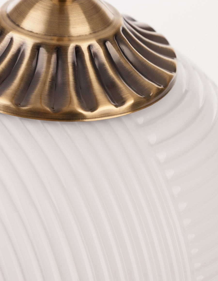 Détail du raccord en laiton doré et du verre strié blanc.