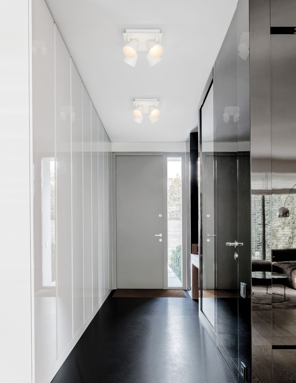 Couloir moderne avec deux plafonniers blancs à quatre projecteurs orientables fixés au plafond.