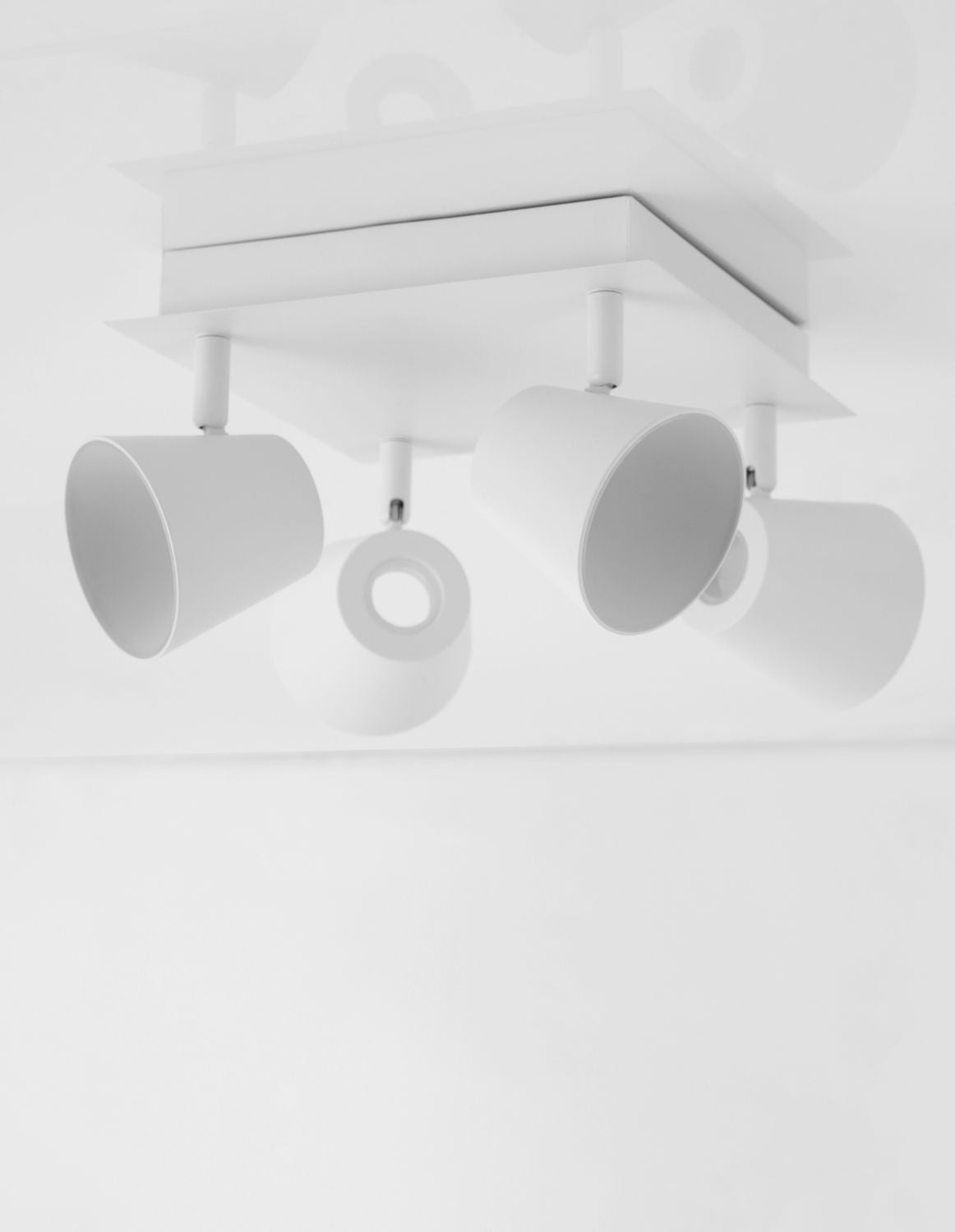 Vue rapprochée en contre-plongée des quatre projecteurs cylindriques et de leur platine blanche.