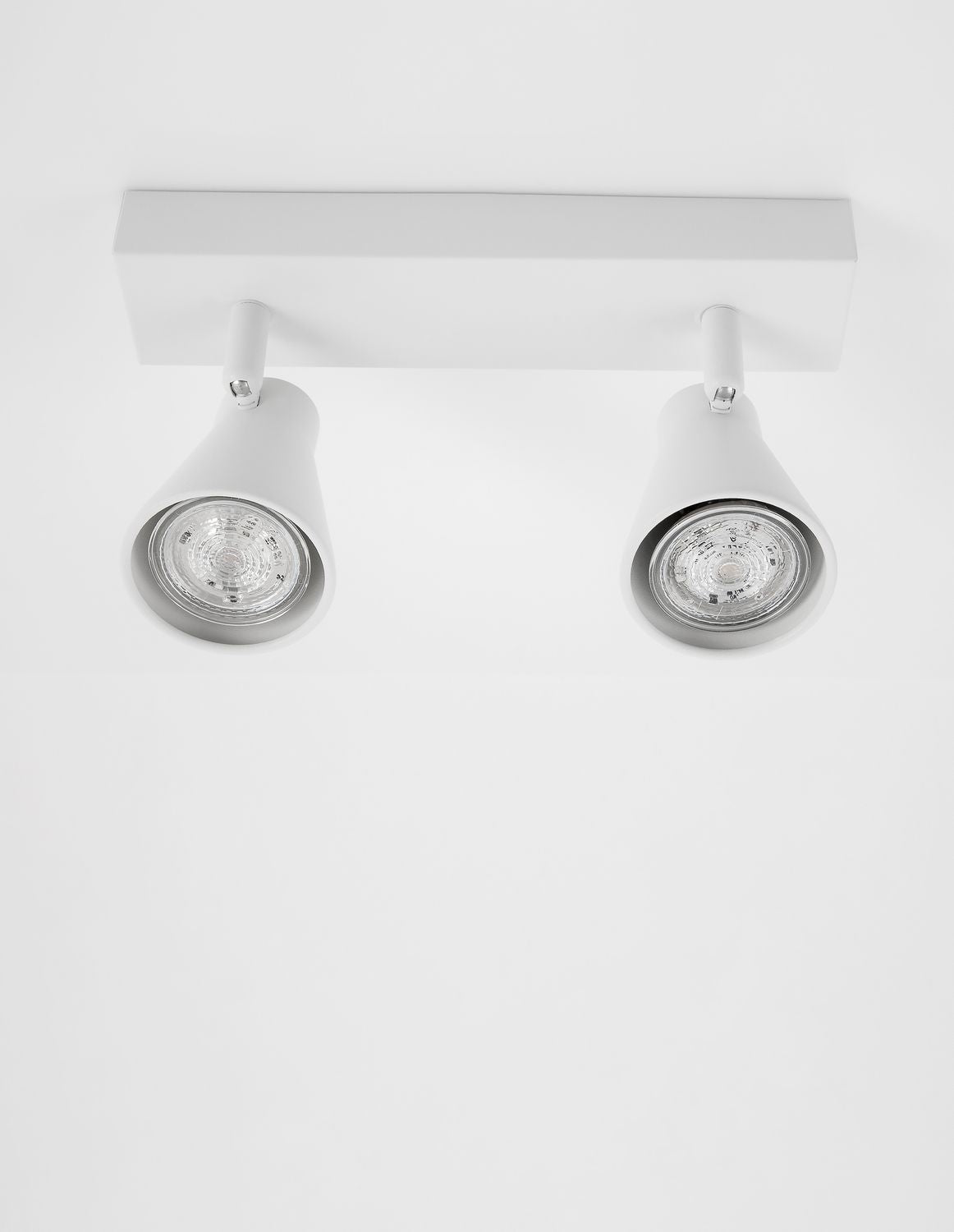 Vue rapprochée des deux projecteurs orientables blancs sous leur base rectangulaire.