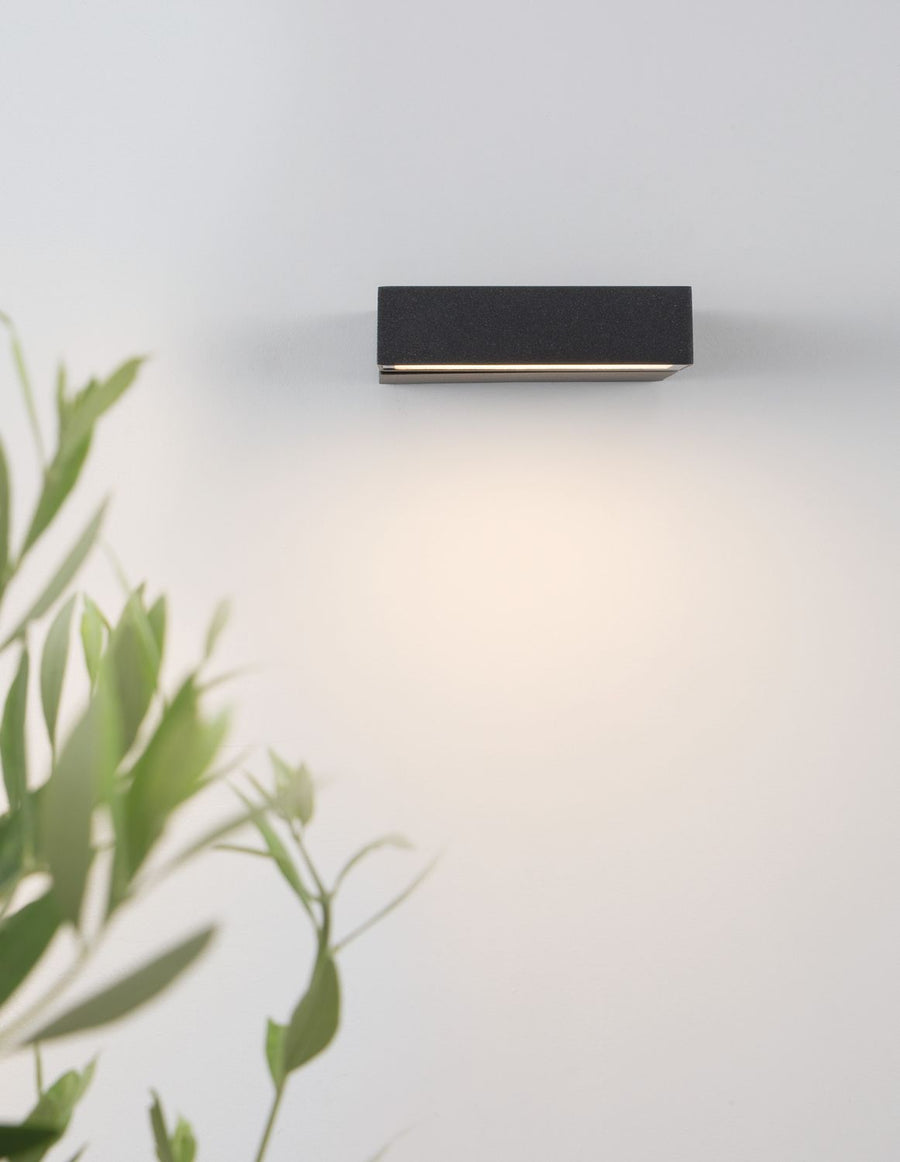 Vue de dessous de l'applique allumée projetant une lumière chaude sur le mur