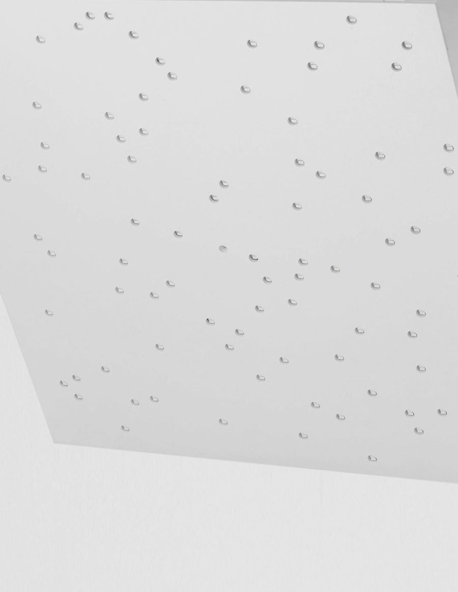Gros plan sur les perforations éteintes du panneau blanc, trous découpés en quinconce