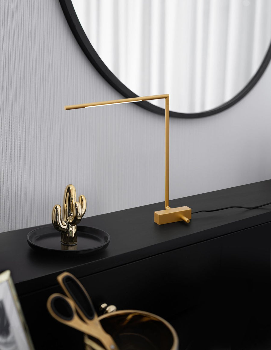 Lampe à poser en laiton sur un meuble noir devant un miroir rond