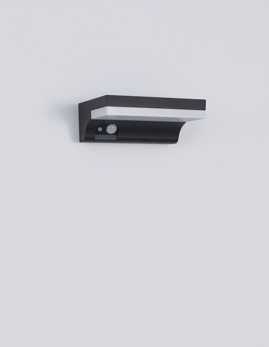 Produit de face sur fond gris, boîtier anthracite granuleux et bandeau lumineux blanc.