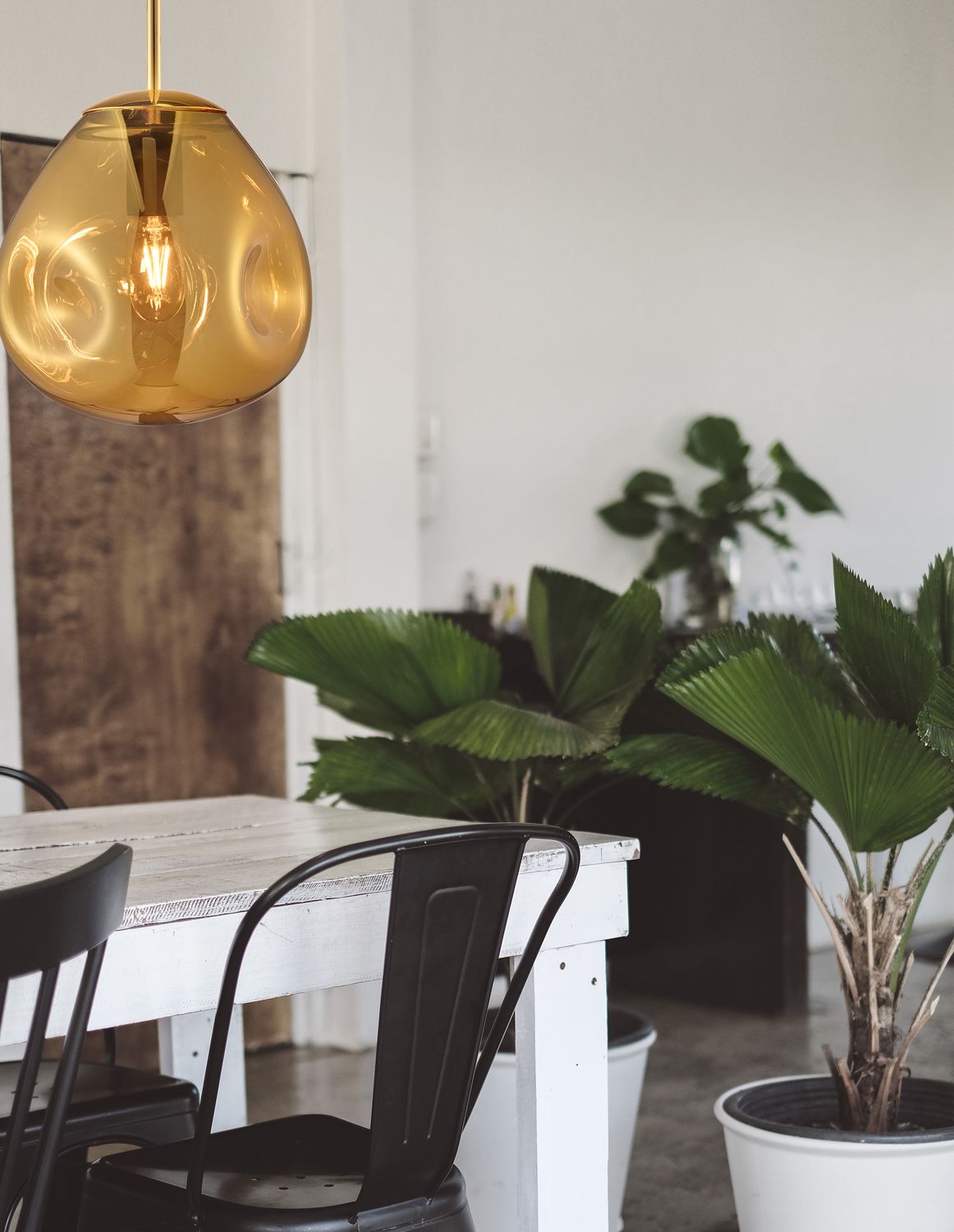Suspension en verre doré allumée au-dessus d'une table blanche en salle à manger