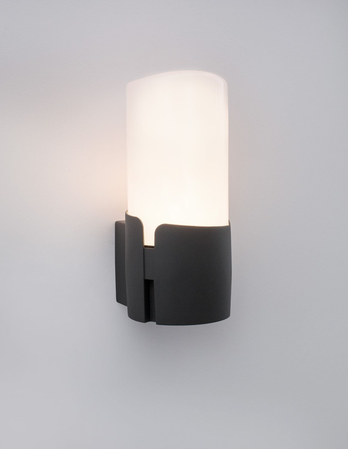Applique allumée diffusant un halo de lumière chaude sur le mur gris