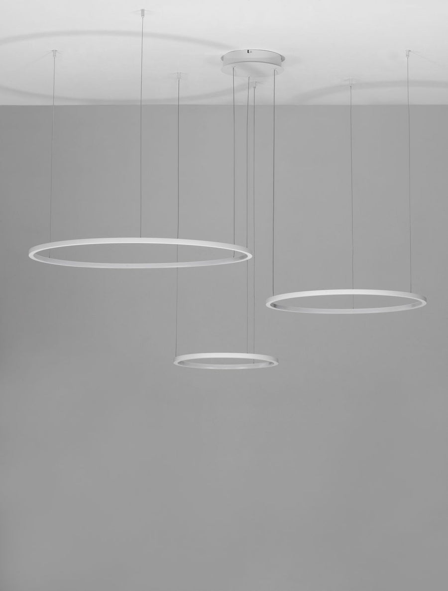 Photo de la suspension montée au plafond avec trois anneaux éclairés dans une pièce grise.