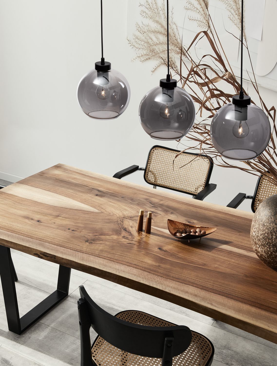 Suspension à trois globes en verre fumé au-dessus d'une table en bois