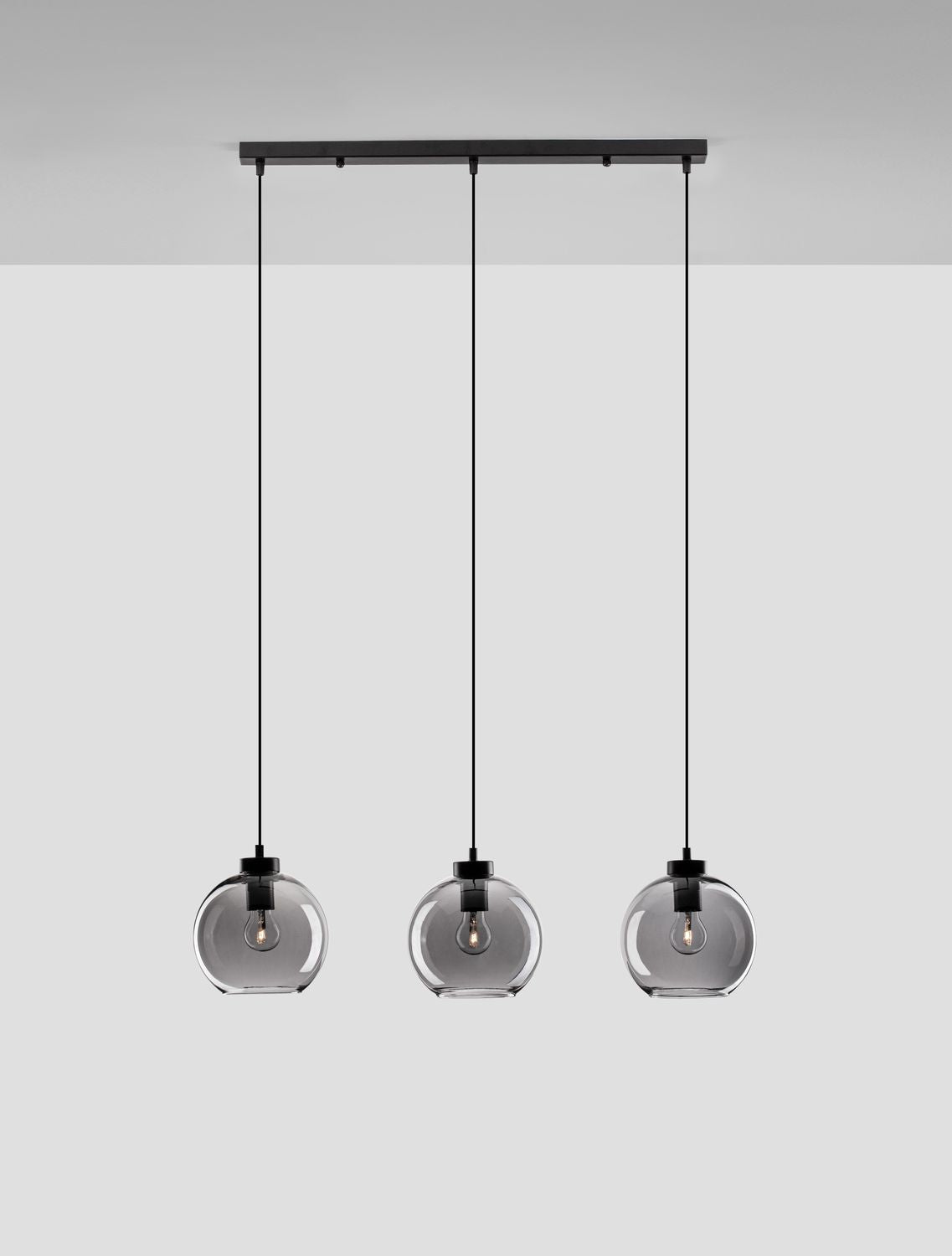 Trois globes en verre fumé suspendus sous une barre noire
