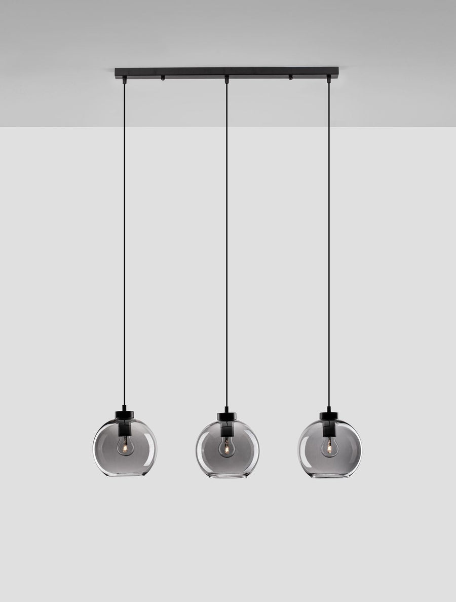 Trois globes en verre fumé suspendus sous une barre noire