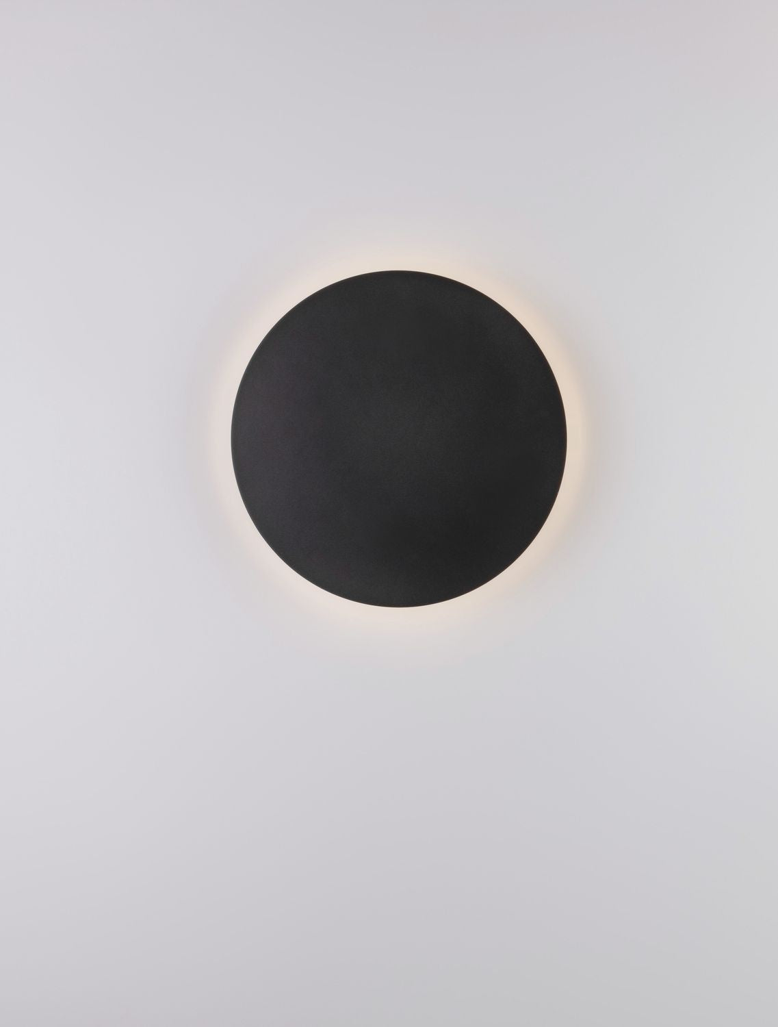 Disque noir en applique, éclairage indirect formant une couronne lumineuse chaude