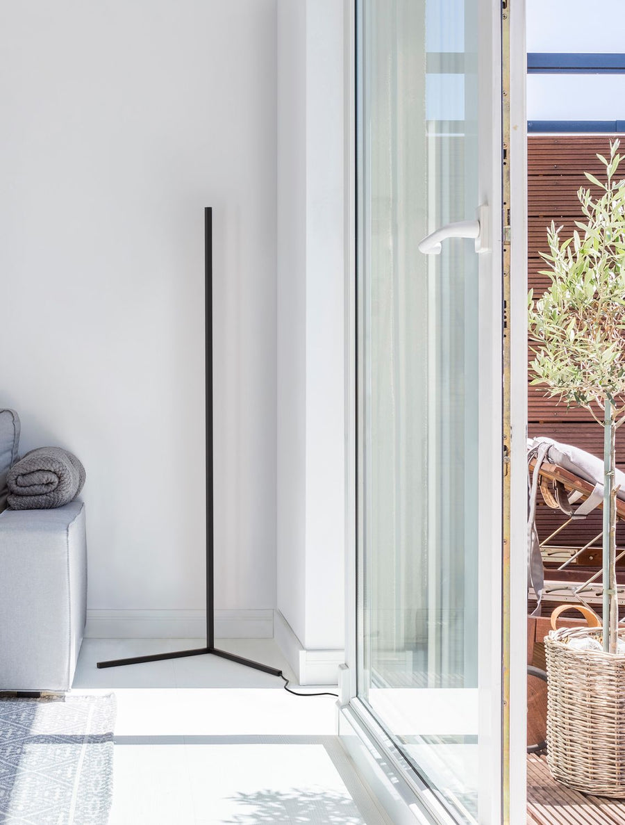 Lampadaire noir minimaliste dans un salon lumineux près d'une baie vitrée
